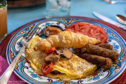 a plate of breakfast food with eggs sausage and tomatoes at Adobe Rose Inn in Tucson