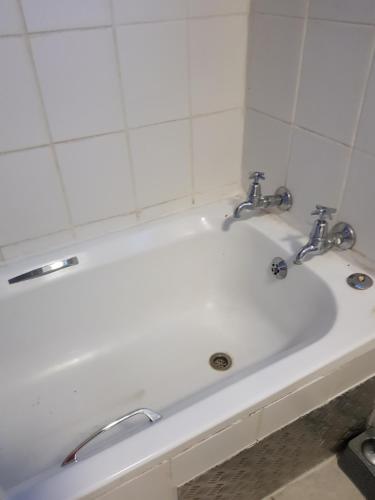 eine weiße Badewanne mit zwei Wasserhähnen darauf in der Unterkunft The Budget Inn in Bloemfontein