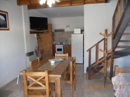 cocina y comedor con mesa de madera y sillas en Cabañas Aldea Serrana en Sierra de la Ventana