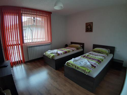 two beds in a room with red windows at Къща за гости Романс in Yagodina
