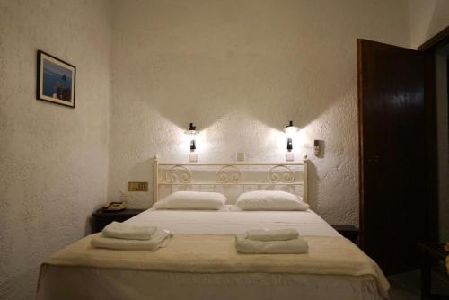 una camera da letto con un grande letto bianco con asciugamani di Alexandros Hotel a Grikos