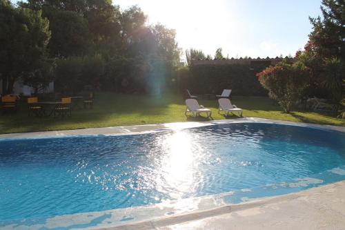 a swimming pool with two chairs and a table at De Los Andes Hotel Boutique in Ciudad Lujan de Cuyo