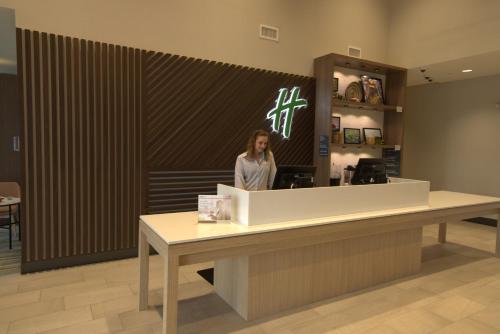 a woman standing at the counter of a store at Holiday Inn & Suites - Hopkinsville - Convention Ctr by IHG in Hopkinsville