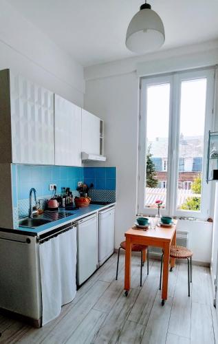 une cuisine avec des armoires blanches et une table en bois dans l'établissement Studio 3 étoiles lumineux et calme à 250 m de la plage, à Mers-les-Bains