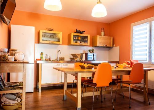 a kitchen with orange walls and a wooden table and chairs at Escale villa in Marignane