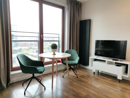 a living room with a table and two chairs and a television at Nowoczesny Apartament z widokiem in Warsaw