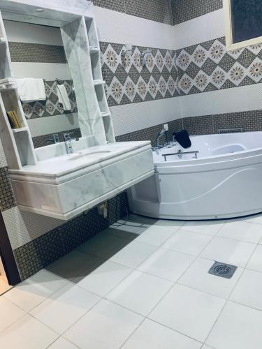 a bathroom with a tub and a sink next to a bath tub at شقق حدائق الزيتون للوحدات السكنية -اقتصادية in Hail