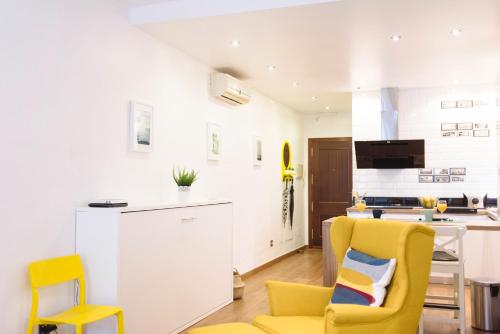 a living room with yellow chairs and a kitchen at Blonski-Yellow in Málaga