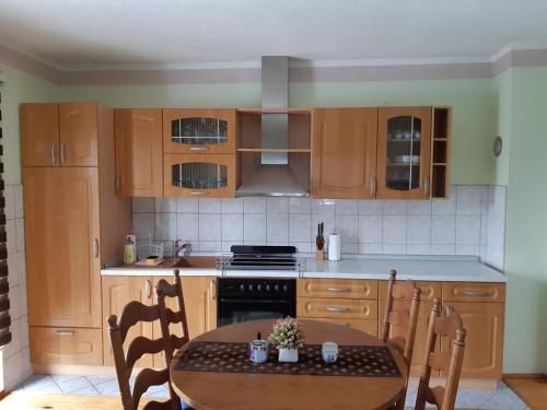a kitchen with wooden cabinets and a table with chairs at Apartman Jonjić in Kupres