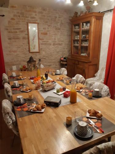 einem Holztisch mit Essen und Orangensaft darauf in der Unterkunft La Maison Rouge Ladoix - Proche Beaune in Ladoix Serrigny