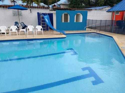 a large swimming pool with a slide and chairs at Villa San Nicolás in Melgar