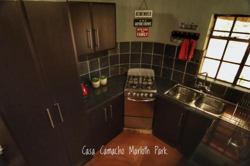 a kitchen with black cabinets and a stove and a sink at Casa Camacho in Marloth Park