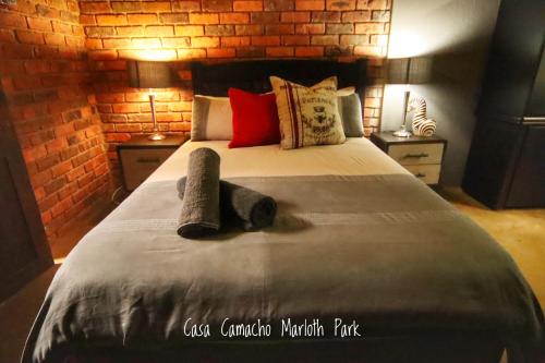 a bedroom with a large bed with a brick wall at Casa Camacho in Marloth Park
