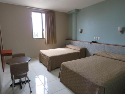 a hotel room with two beds and a table and a window at Hotel San Juan Periferico in Villahermosa