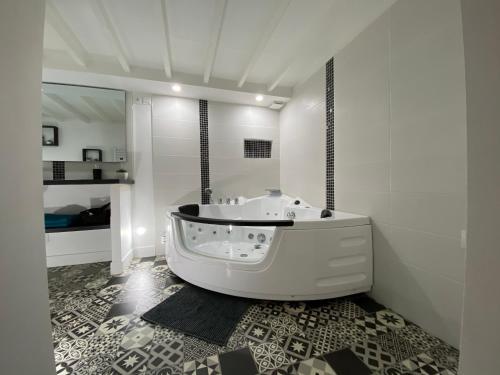 Habitación con baño blanco con bañera. en LH LOFT spa, en Le Havre