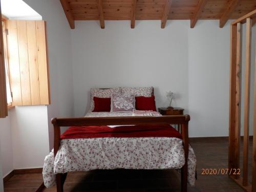 a small bedroom with a bed with red pillows at Adega Jaquet in Biscoitos