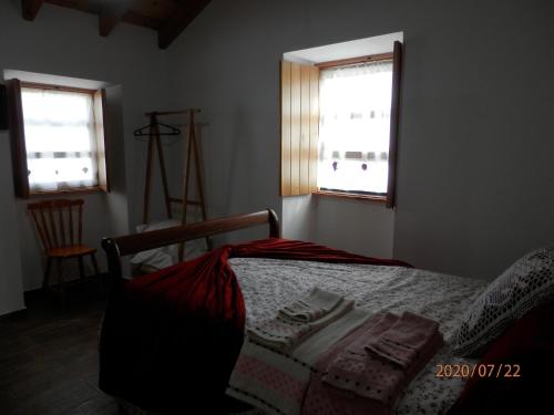 a bedroom with a bed and two windows at Adega Jaquet in Biscoitos