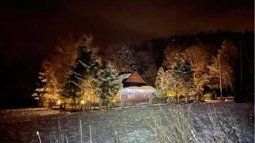 a lit up building in a snowy field at night at Góralska Czarcia Chata pod Jałowcem in Stryszawa