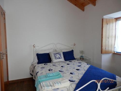 a bedroom with a large bed with blue pillows at Adega Vermont in Biscoitos