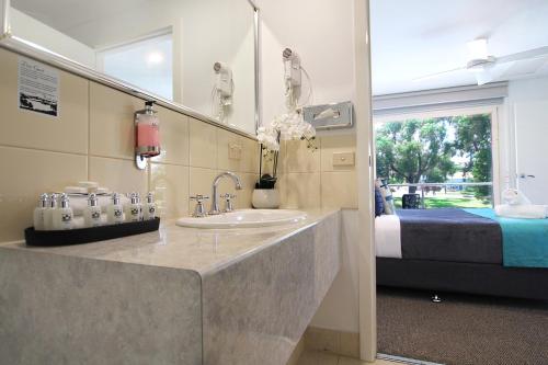 een badkamer met een wastafel, een spiegel en een bed bij Apartments 521 in Warrnambool