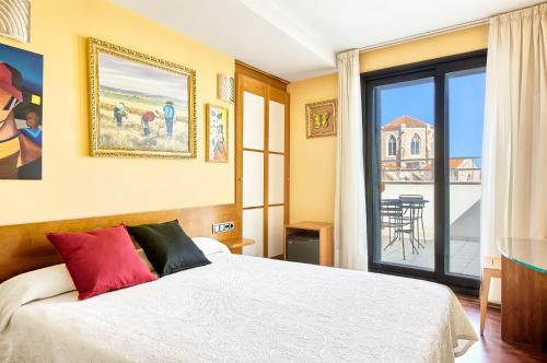 1 dormitorio con cama y vistas a un balcón en Hotel Plaza Inn en Figueres