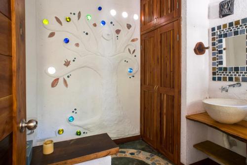 a bathroom with a tree painted on the wall at Bungalow Bé La Kin in Cozumel