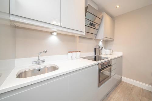 a kitchen with white cabinets and a sink at MORDEN 1 BEDROOM 5 mins away from brighton seafront in Brighton & Hove