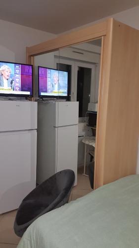 Zimmer mit zwei Monitoren, einem Stuhl und einem Bett in der Unterkunft MAGNIFIQUE STUDIO in Saint-Just-Sauvage