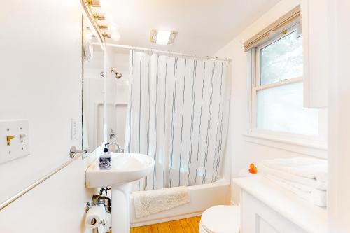 uma casa de banho branca com um lavatório e um chuveiro em A Room With A View em Provincetown