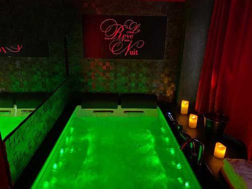 uma banheira verde num quarto com velas em Le rêve d’une nuit suite mystérieuse em Sarreguemines