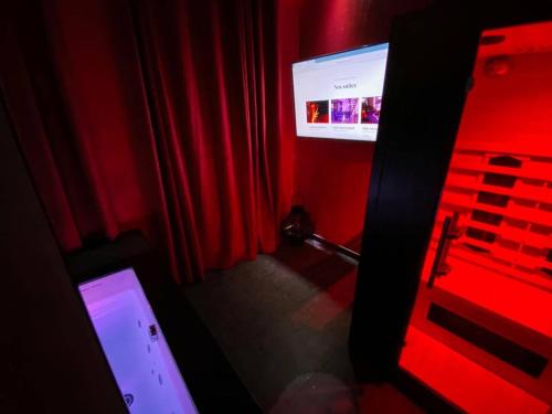 Cette chambre rouge comprend une télévision et un rideau rouge. dans l'établissement Le rêve d’une nuit suite mystérieuse, à Sarreguemines