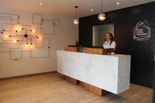 a woman standing at a reception desk in a room at Alou Hotel Boutique in Tijuana
