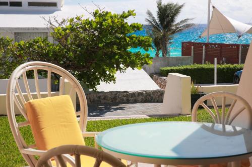 a table and chairs with the ocean in the background at Brisas Shores Beach & OceanFront Apartments 1 or 2 bedrooms Cancun Hotel Zone in Cancún