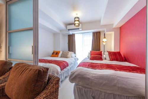 2 Betten in einem Zimmer mit roter Wand in der Unterkunft LANDMARK NAMBA TSUTENKAKU in Osaka