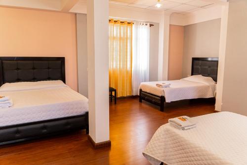 two beds in a room with wooden floors at Residencial Velia & Victoria in Cochabamba