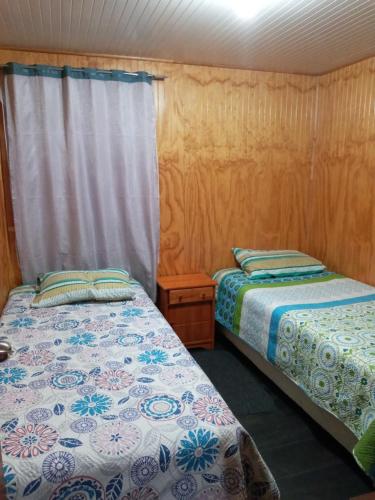 two beds in a room with wooden walls at Cabaña Quinchen in Castro