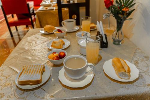 a table with plates of food and cups of coffee at Residencial Velia & Victoria in Cochabamba