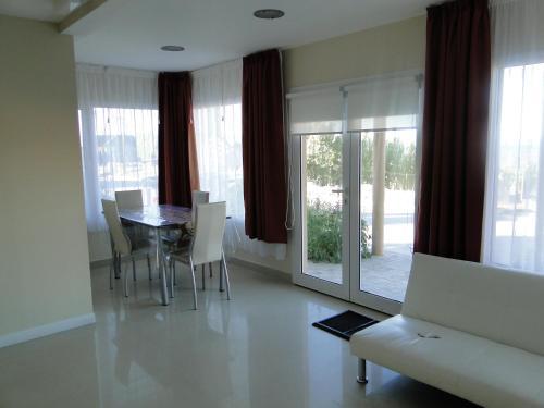 a dining room with a table and chairs and windows at Altos del Lago departamentos in El Calafate