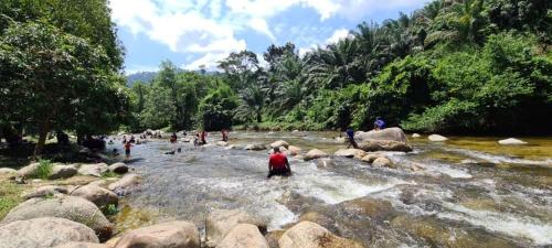 a group of people standing on rocks in a river at Lubok Jong Riverside, Sedim in Kulim
