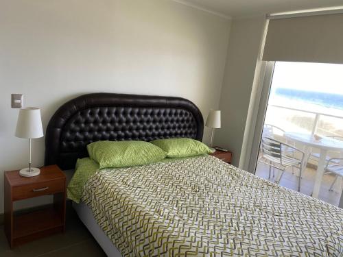 Un dormitorio con una cama con almohadas verdes y una ventana en Condominio Laguna del Mar, en La Serena