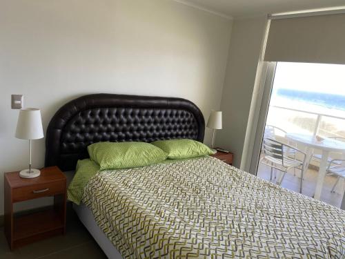 a bedroom with a bed with green pillows and a window at Condominio Laguna del Mar in La Serena