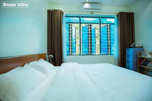 a bedroom with a white bed and a window at Rosie Villa Ha Giang - Motorbikerental & Tour in Ha Giang