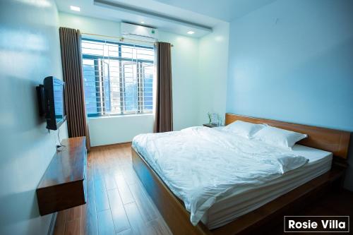 a bedroom with a white bed and a window at Rosie Villa Ha Giang - Motorbikerental & Tour in Ha Giang