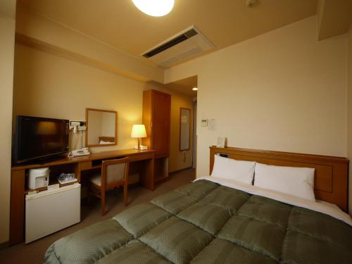 Dormitorio con cama, escritorio y TV en Hotel Route-Inn Yokkaichi, en Yokkaichi