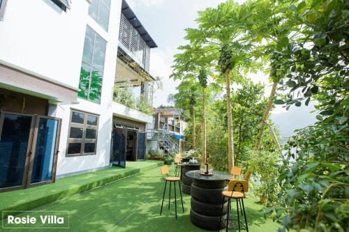 a patio with chairs and a table and trees at Rosie Villa Ha Giang - Motorbikerental & Tour in Ha Giang