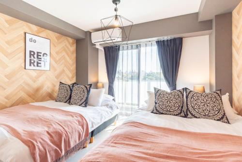 a bedroom with two beds and a window at Bijou Suites Bloom in Osaka