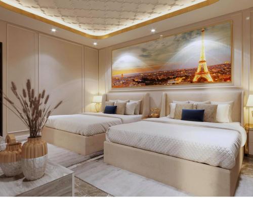 two beds in a bedroom with a picture of the eiffel tower at The wiltons hotel in Nam Ðịnh