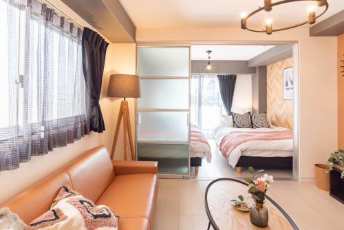 a living room with a couch and a bedroom at Bijou Suites Bloom in Osaka