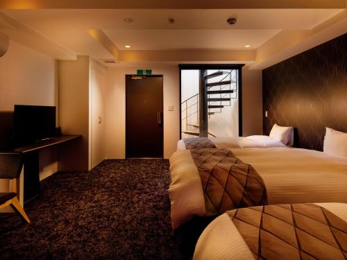 a hotel room with two beds and a television at Connect Inn Kyoto Station South in Kyoto