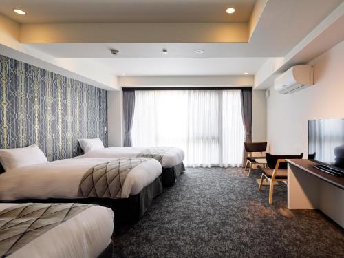 a hotel room with two beds and a flat screen tv at Connect Inn Kyoto Station South in Kyoto